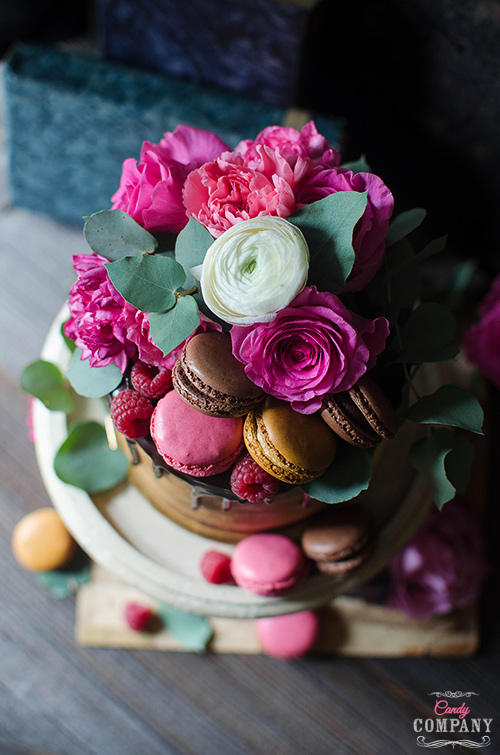 Flourless chocolate almond cake with caramelized white chocolate ganache and raspberries decorated with fresh flowers and french macaroons