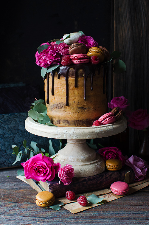 Flourless chocolate almond cake with caramelized white chocolate ganache and raspberries decorated with fresh flowers and french macaroons